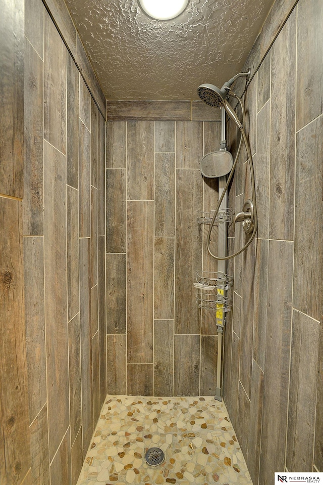 bathroom with a textured ceiling and a tile shower