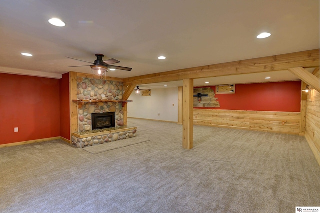 unfurnished living room featuring ceiling fan, carpet floors, a fireplace, and wooden walls