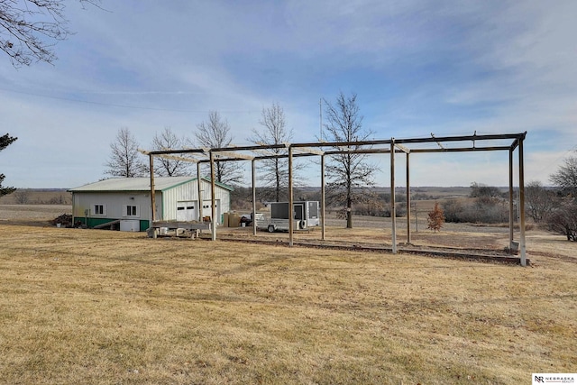 view of yard with a garage, an outbuilding, and a rural view