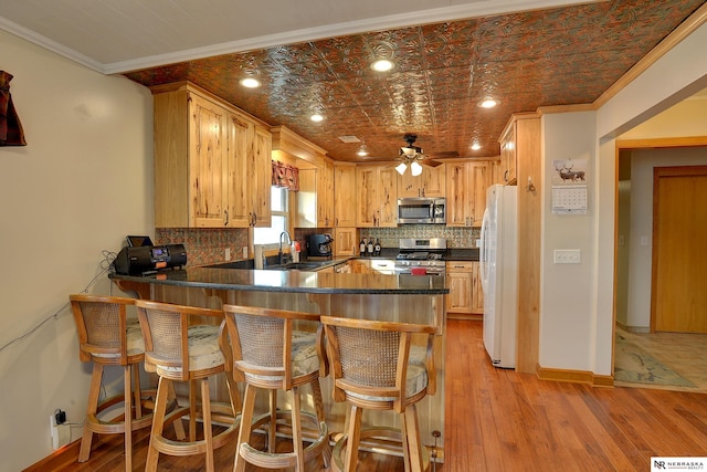 kitchen with appliances with stainless steel finishes, a kitchen breakfast bar, decorative backsplash, ornamental molding, and kitchen peninsula