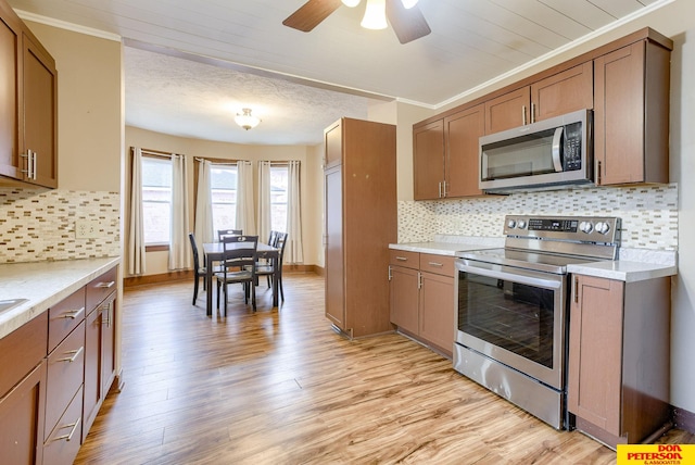 kitchen featuring crown molding, appliances with stainless steel finishes, decorative backsplash, and light hardwood / wood-style flooring