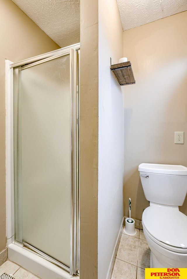 bathroom featuring toilet, tile patterned floors, a textured ceiling, and walk in shower