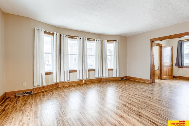 unfurnished room featuring a textured ceiling and light wood-type flooring