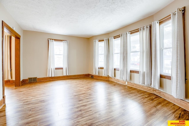 unfurnished room featuring hardwood / wood-style floors and a textured ceiling