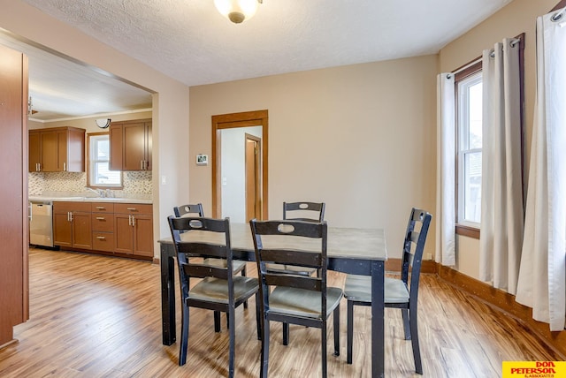 dining room featuring sink, light hardwood / wood-style flooring, and a textured ceiling