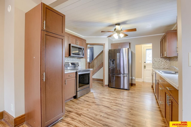 kitchen featuring appliances with stainless steel finishes, sink, decorative backsplash, crown molding, and light hardwood / wood-style flooring