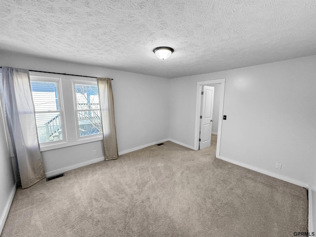 empty room featuring light colored carpet and a textured ceiling