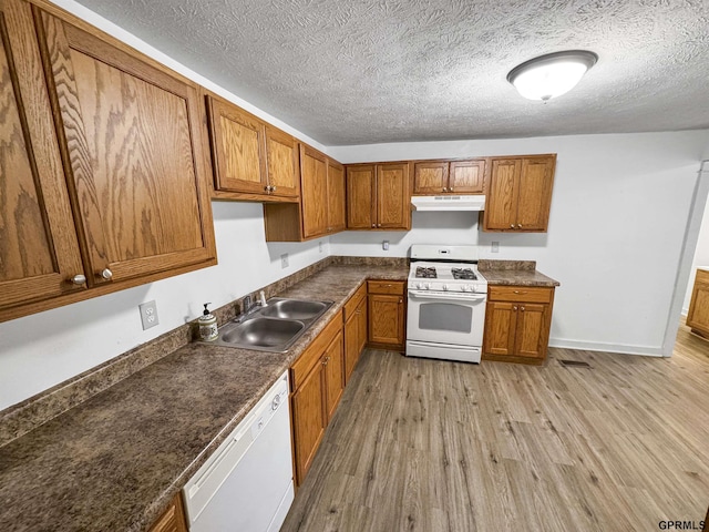 kitchen with sink, white appliances, light hardwood / wood-style flooring, and a textured ceiling