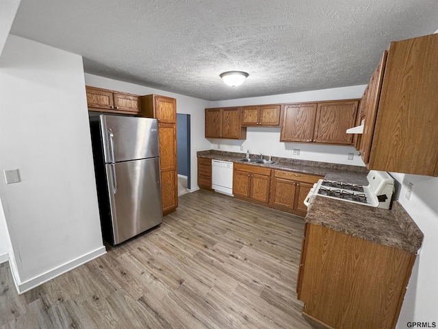 kitchen featuring extractor fan, sink, a textured ceiling, white appliances, and light hardwood / wood-style floors