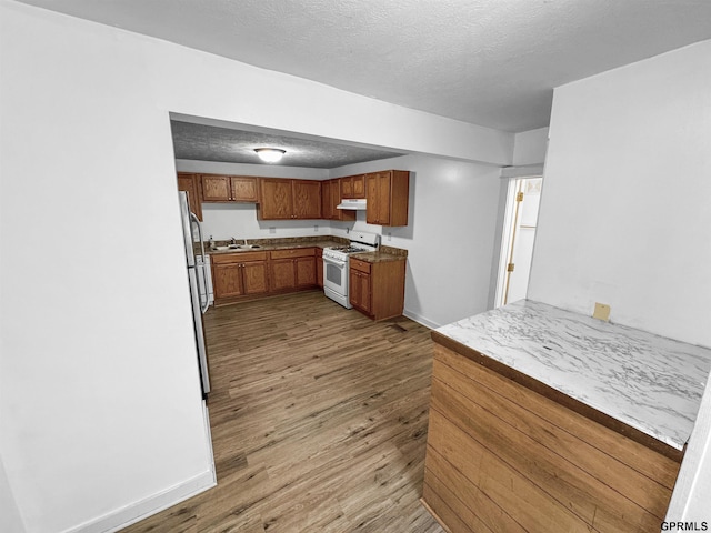 kitchen featuring a textured ceiling, sink, gas range gas stove, and light hardwood / wood-style flooring