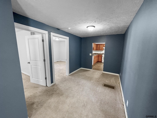 carpeted empty room featuring a textured ceiling