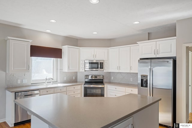 kitchen with white cabinetry, stainless steel appliances, a kitchen island, and backsplash