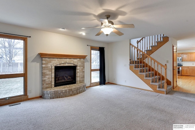 unfurnished living room featuring light carpet, a fireplace, and ceiling fan