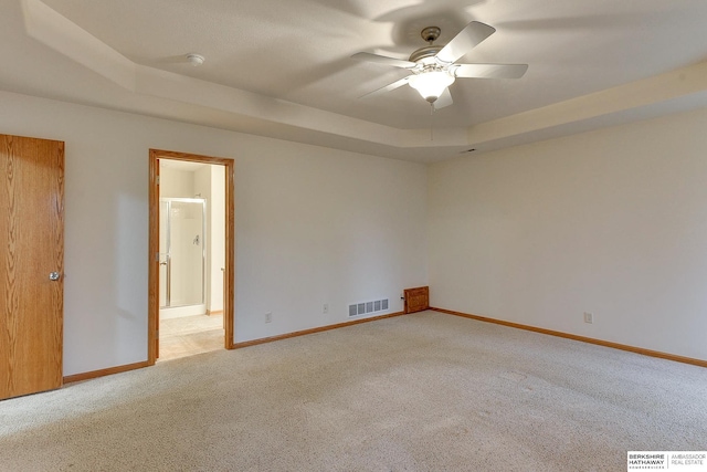 empty room featuring light colored carpet, ceiling fan, and a tray ceiling