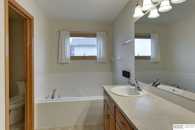 bathroom with vanity, plenty of natural light, tiled bath, and toilet