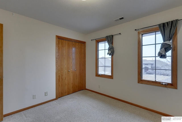 unfurnished bedroom featuring a closet and light carpet