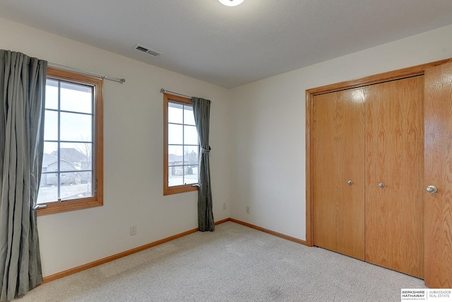 unfurnished bedroom featuring light colored carpet and a closet