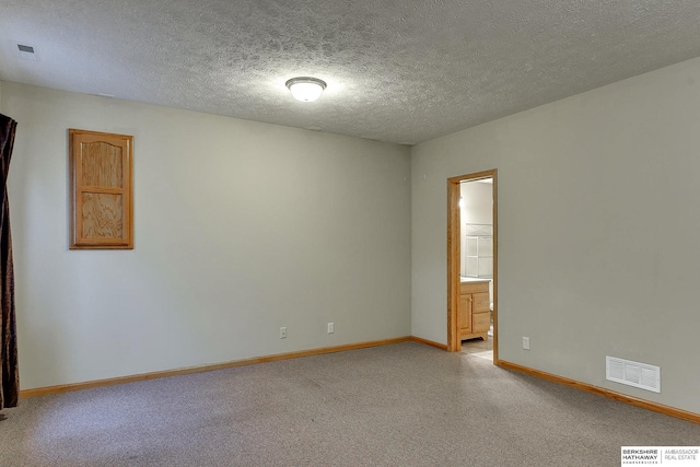 empty room with light colored carpet and a textured ceiling