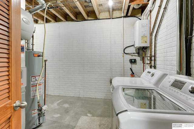 laundry area with water heater, gas water heater, and washer and dryer