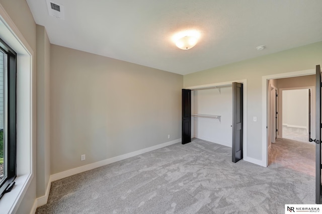 unfurnished bedroom with light colored carpet and a closet