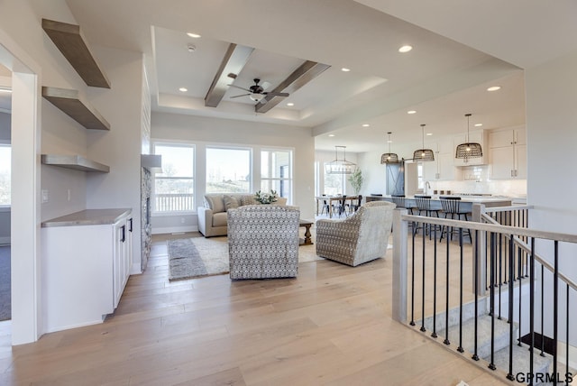 living room with beamed ceiling, ceiling fan, and light hardwood / wood-style flooring