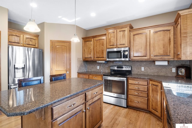 kitchen with a kitchen island, appliances with stainless steel finishes, decorative light fixtures, backsplash, and a kitchen breakfast bar