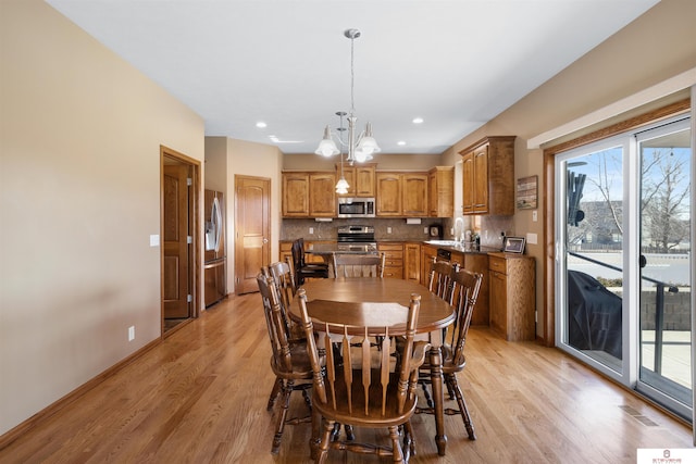 dining area featuring sink, a chandelier, and light hardwood / wood-style flooring