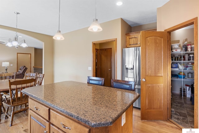 kitchen featuring hanging light fixtures, stainless steel fridge with ice dispenser, a kitchen island, and light wood-type flooring