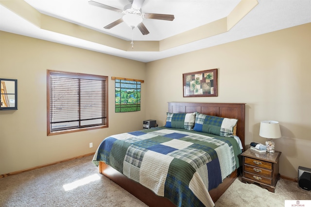 carpeted bedroom with a tray ceiling and ceiling fan