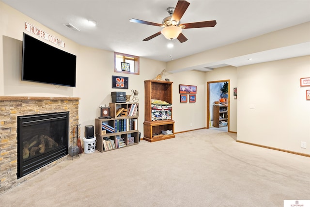 carpeted living room with ceiling fan and a fireplace