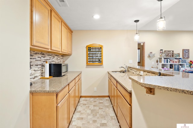 kitchen featuring sink, decorative backsplash, light stone counters, and decorative light fixtures