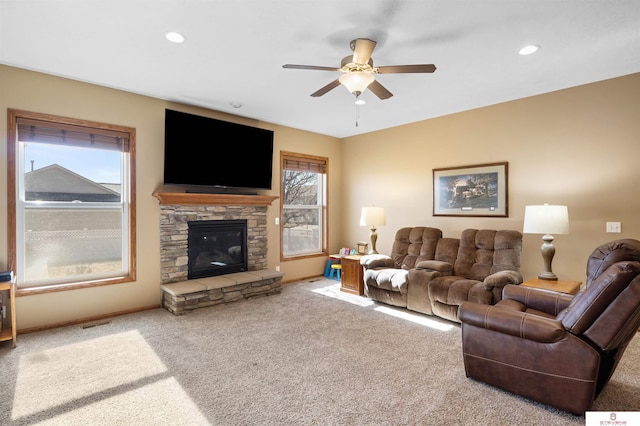 carpeted living room with ceiling fan and a fireplace