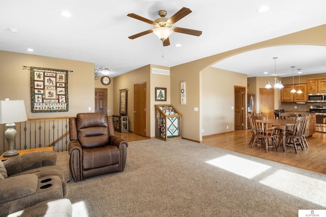 carpeted living room featuring ceiling fan with notable chandelier