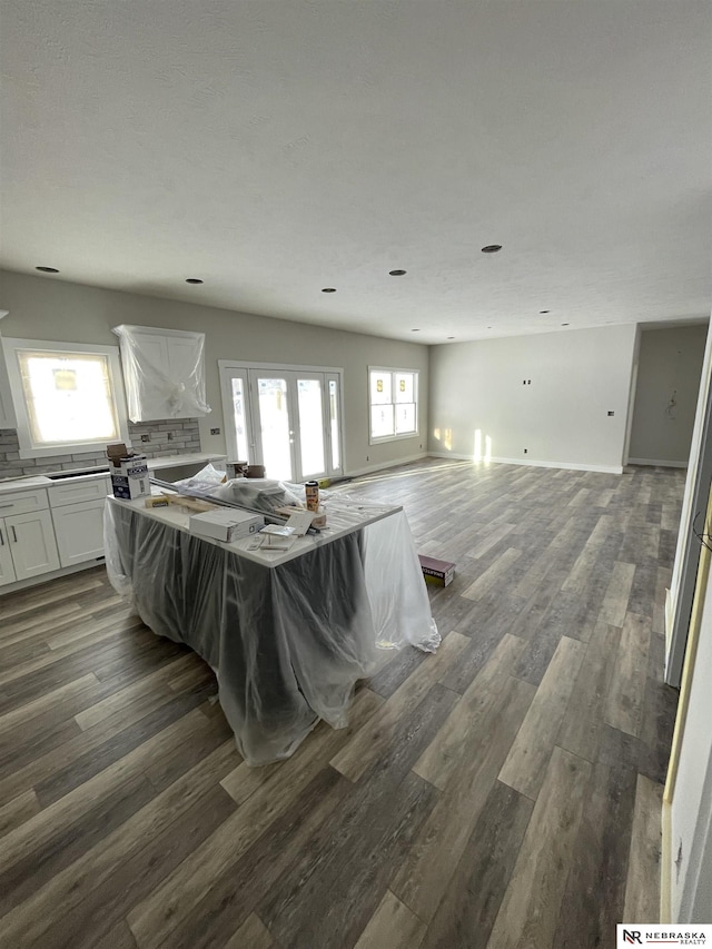 kitchen featuring wood finished floors, a kitchen island, french doors, white cabinetry, and open floor plan