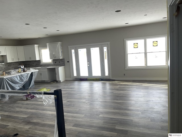 kitchen with wood finished floors, white cabinetry, light countertops, decorative backsplash, and baseboards