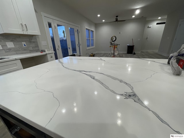 interior space with light stone counters, decorative backsplash, and white cabinetry