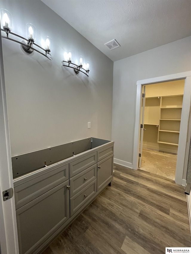 bathroom with visible vents, baseboards, a textured ceiling, and wood finished floors