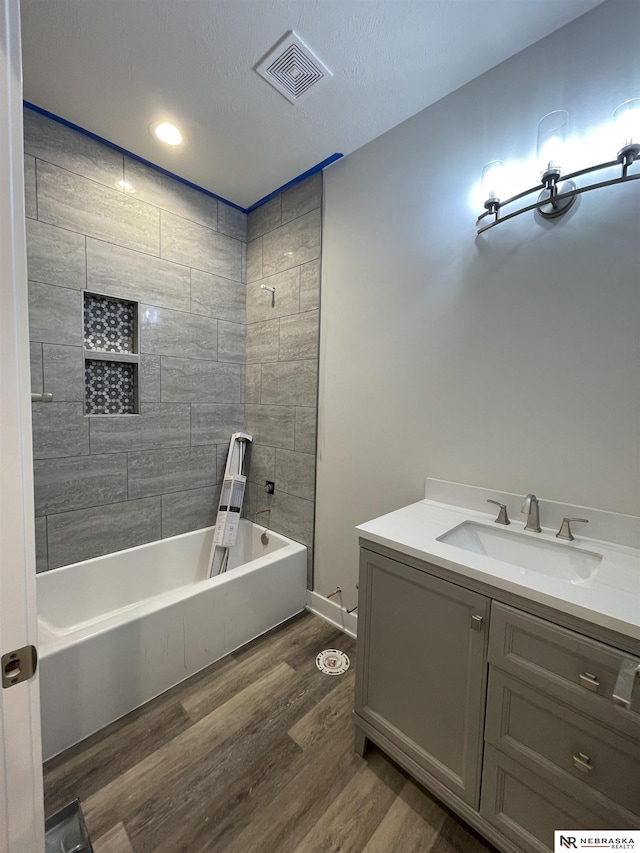 bathroom with shower / bathing tub combination, visible vents, wood finished floors, and vanity