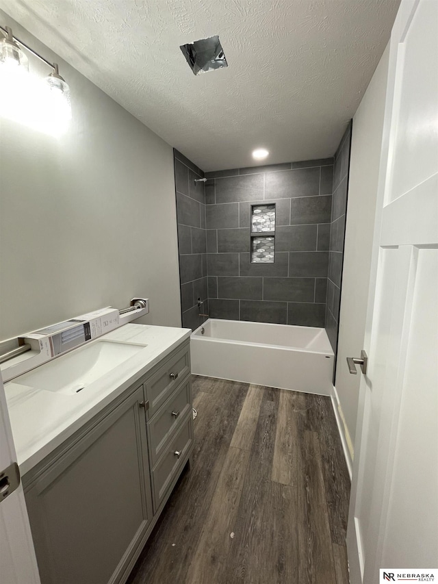 bathroom with vanity,  shower combination, wood finished floors, and a textured ceiling