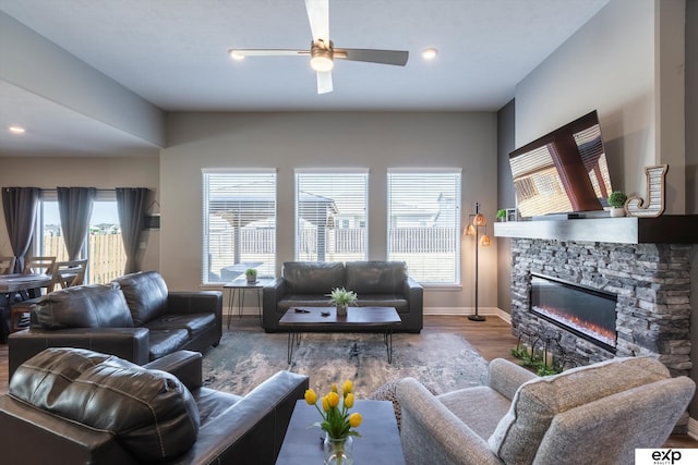 living room with a stone fireplace, hardwood / wood-style floors, and ceiling fan