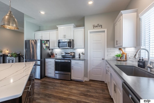 kitchen featuring white cabinetry, sink, hanging light fixtures, and appliances with stainless steel finishes