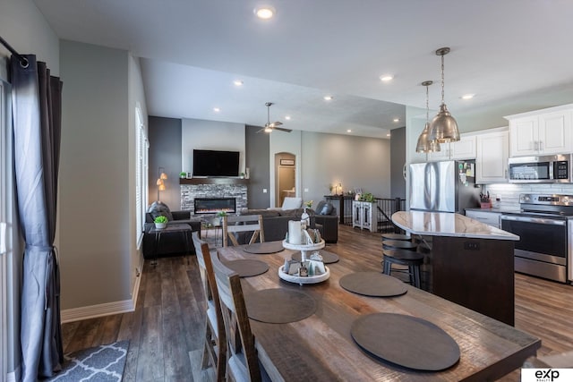 dining room featuring dark hardwood / wood-style flooring, ceiling fan, and a fireplace