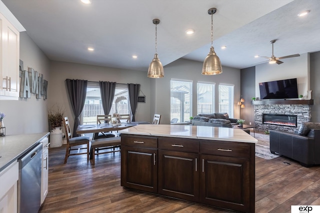 kitchen with a stone fireplace, decorative light fixtures, dishwasher, dark hardwood / wood-style flooring, and dark brown cabinetry