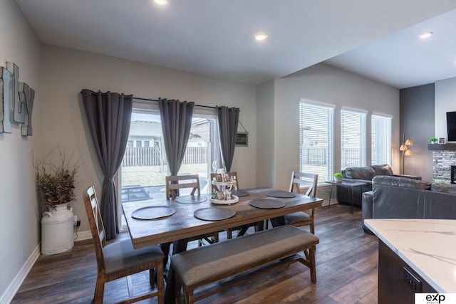 dining room featuring dark wood-type flooring and a stone fireplace