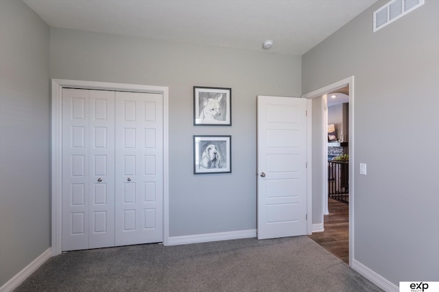 unfurnished bedroom featuring a closet and dark colored carpet