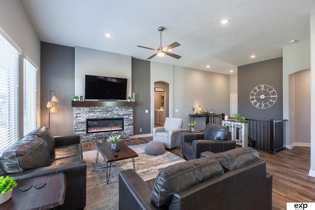 living room featuring a fireplace, dark wood-type flooring, and ceiling fan