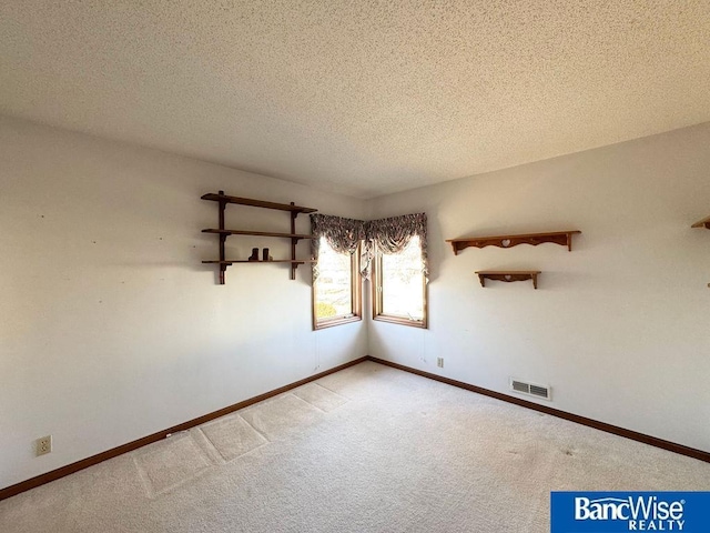 unfurnished room featuring light carpet and a textured ceiling