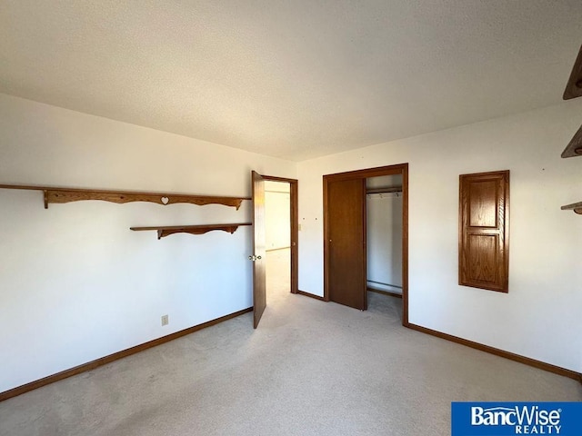 unfurnished bedroom featuring light colored carpet, a closet, and a textured ceiling