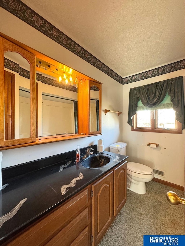 bathroom with vanity, toilet, and a textured ceiling