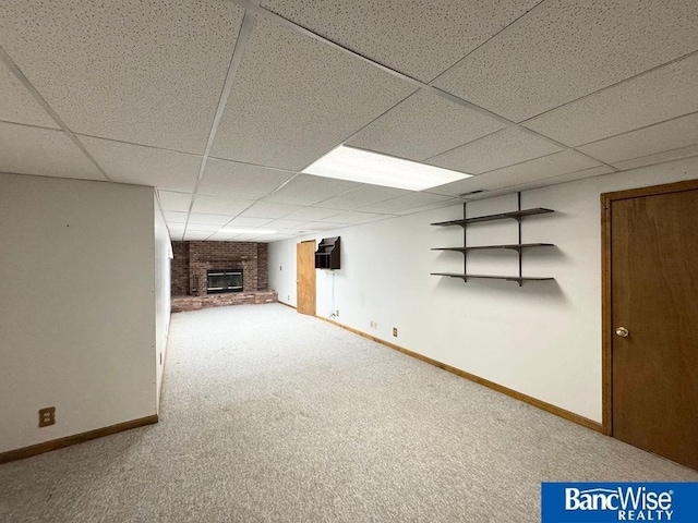 basement featuring a brick fireplace, carpet floors, and a paneled ceiling